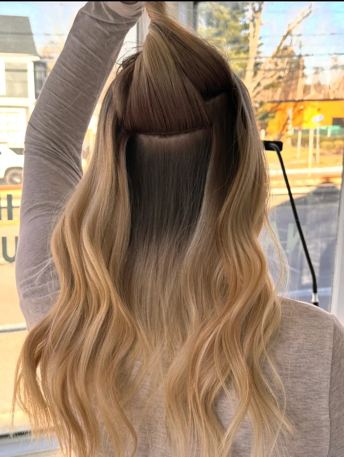 Long blonde waves during a two-row Invisible Bead Extensions install